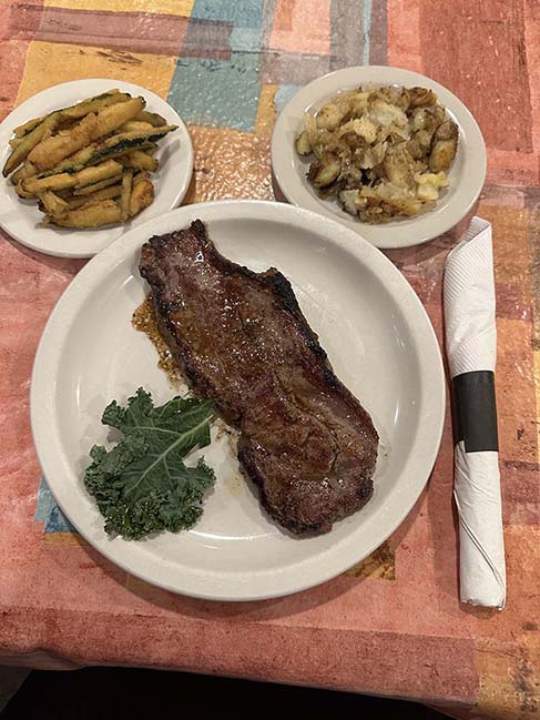 Strip steak dinner with fried zucchini and home fries is served at Ricardo’s Restaurant in Erie, PA.